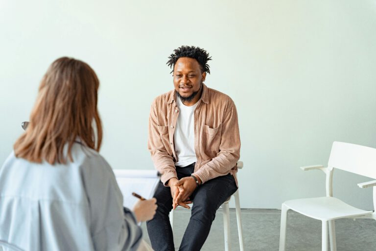 A therapy session in a modern office setting with a counselor and a client engaged in conversation.