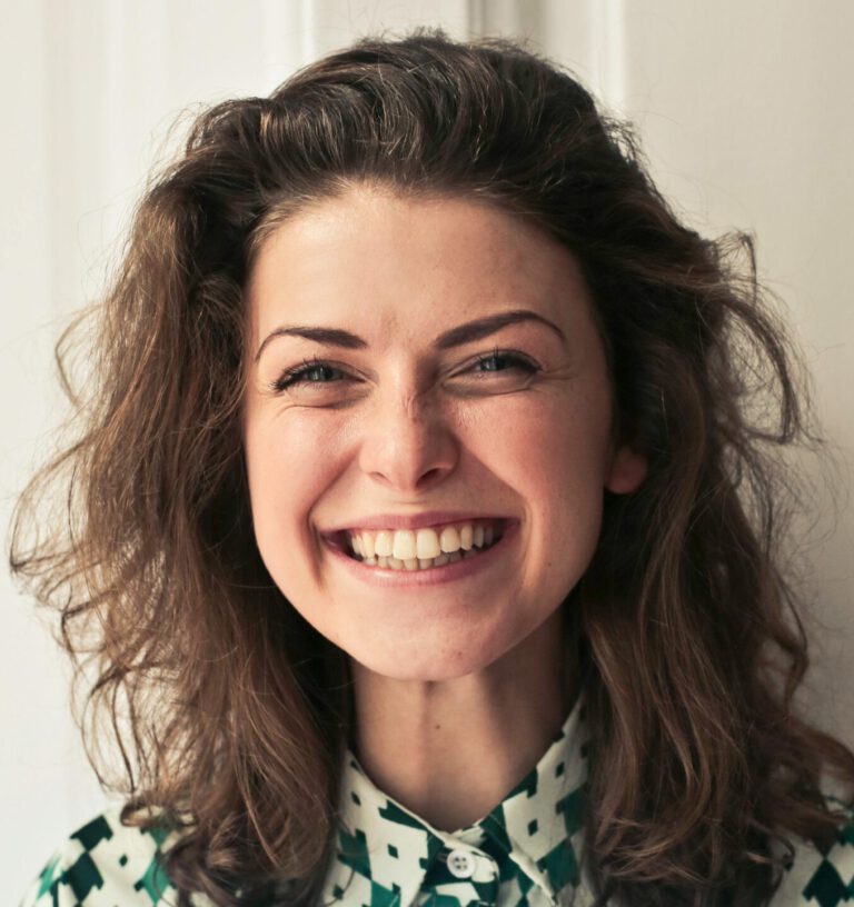 Portrait of a joyful brunette woman with a vibrant smile indoors, capturing happiness and positivity.